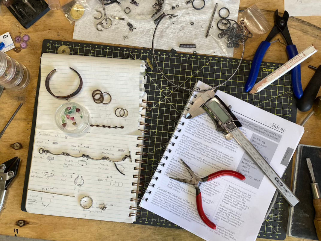 Amanda Jo's workbench with jewelry, tools, and a sketch book.